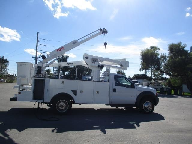 A white truck with a crane on the back is parked in a parking lot