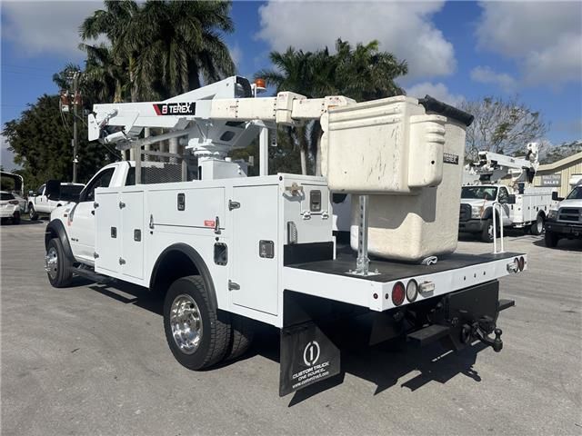 A white truck with a crane on the back is parked in a parking lot.