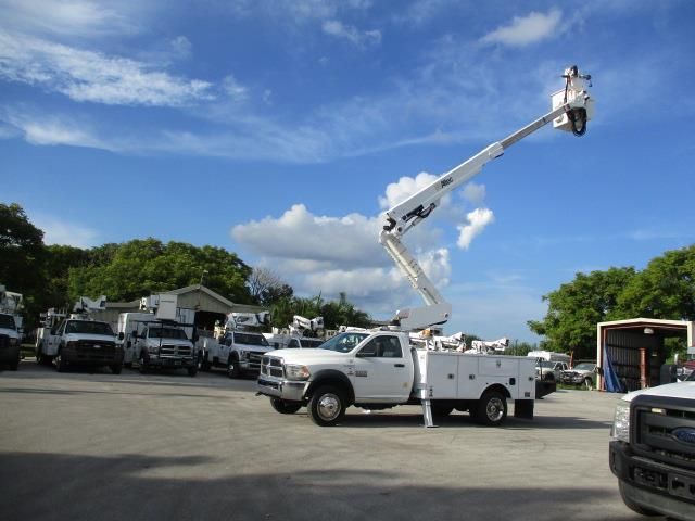 A white truck with a crane on the back is parked in a parking lot