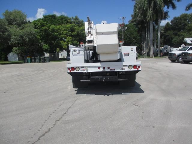 A white truck is parked in a parking lot with trees in the background