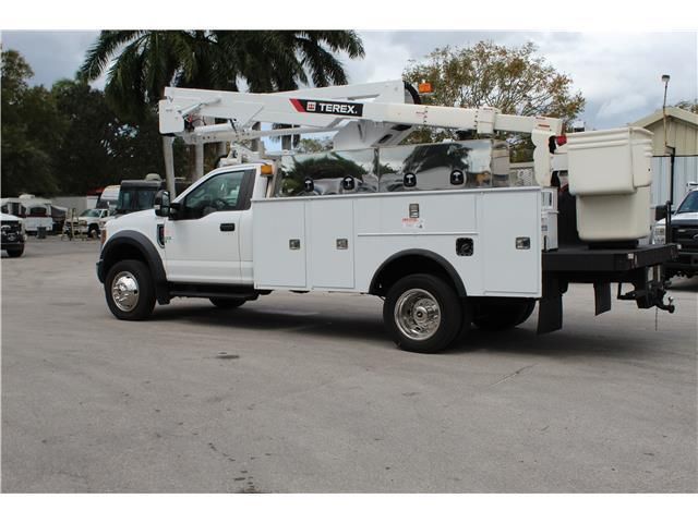 A white utility truck is parked in a parking lot