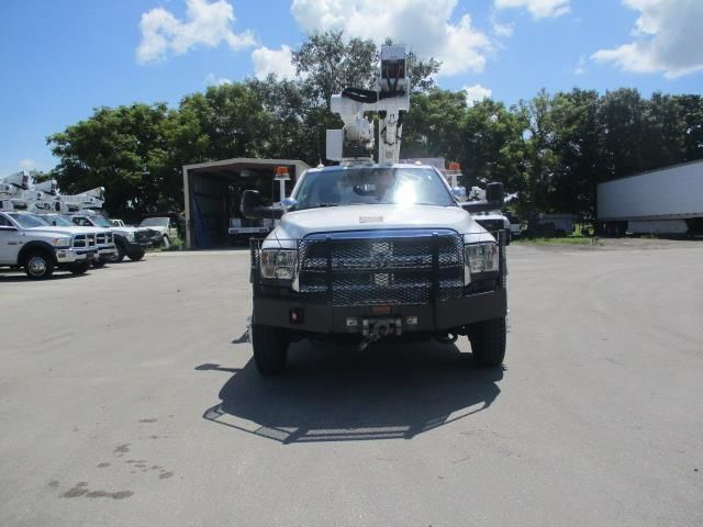 A white truck with a crane on top of it is parked in a parking lot.