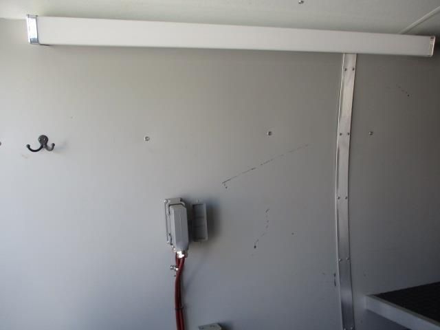 A white wall with hooks and a red hose