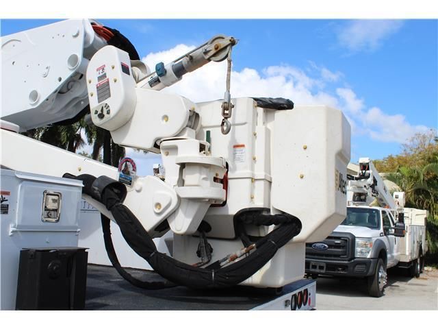 Two utility trucks are parked next to each other on a sunny day