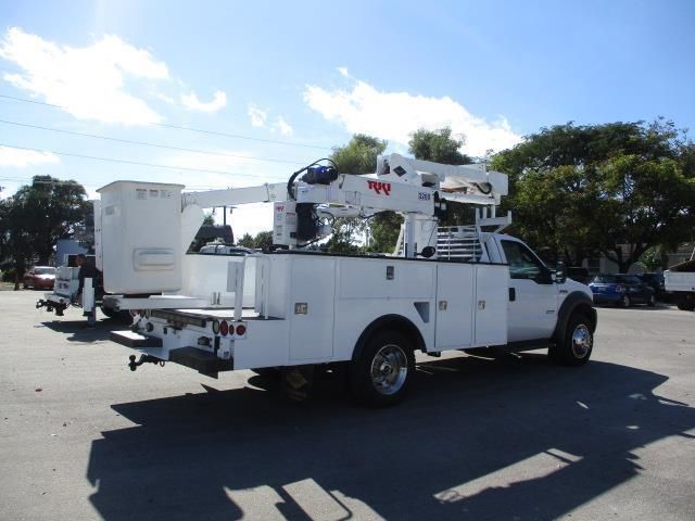 A white truck with a crane on the back is parked in a parking lot