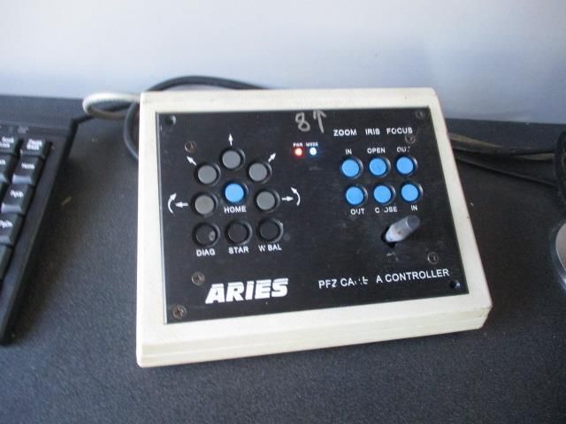 A aries controller sits on a desk next to a keyboard