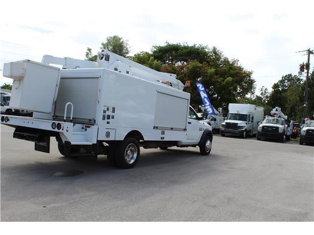 A white truck with a ladder on the back is parked in a parking lot.