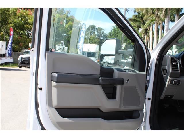 A white truck with the door open is parked in a parking lot.