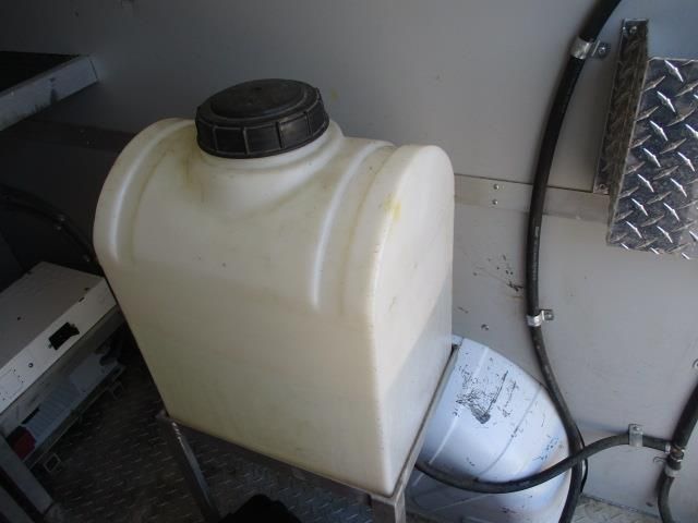 A white plastic container with a black lid is sitting next to a black hose.