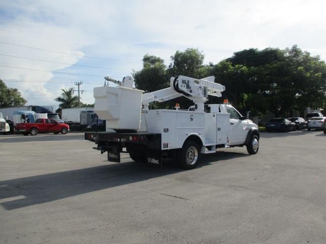 A white utility truck with a bucket on the back is parked in a parking lot.