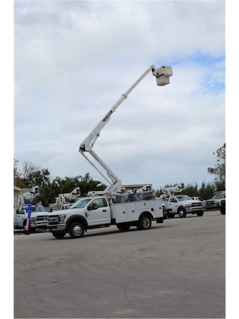 A white truck with a crane on the back is parked in a parking lot