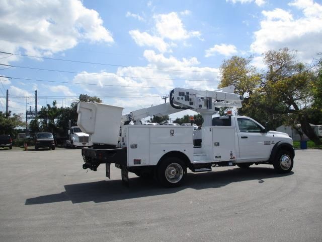 A white utility truck with a crane on the back is parked in a parking lot.