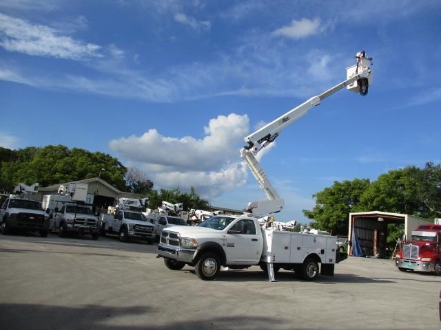 A white truck with a crane attached to it is parked in a parking lot