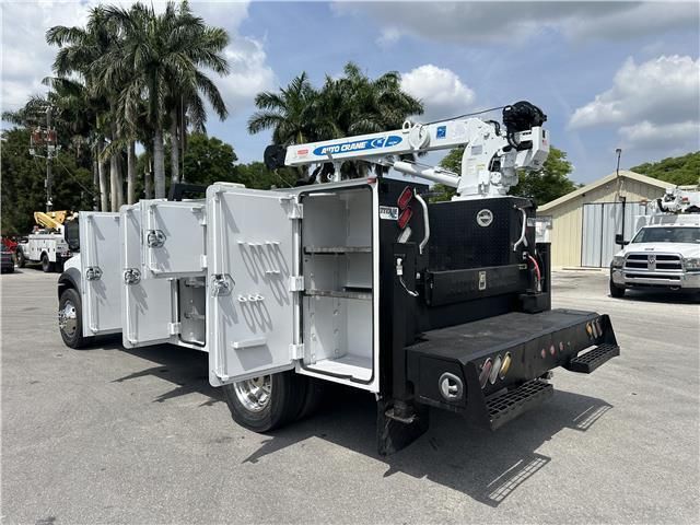 A utility truck with its doors open is parked in a parking lot.
