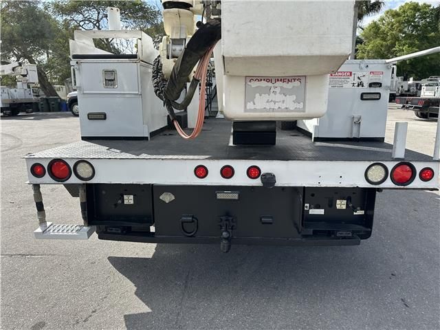 A white truck with a bucket on the back is parked in a parking lot
