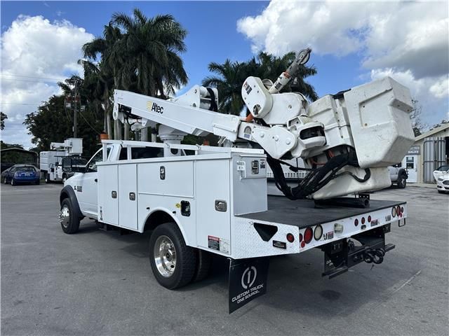 A white utility truck with a crane on the back is parked in a parking lot.