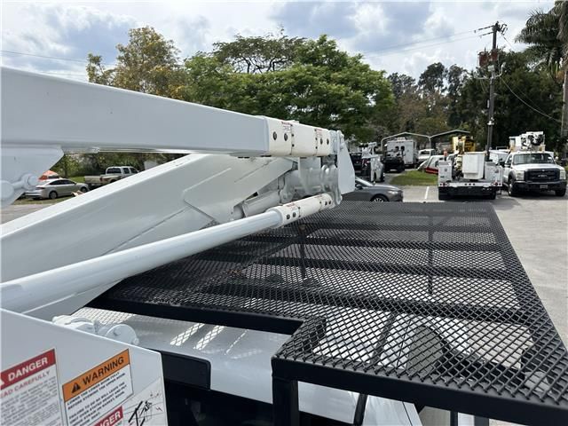A white truck with a ladder attached to it is parked in a parking lot.