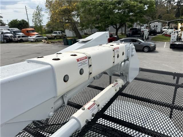 A white crane is sitting on top of a fence in a parking lot.