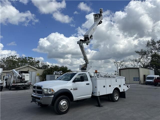 A white utility truck with a crane on the back is parked in a parking lot.