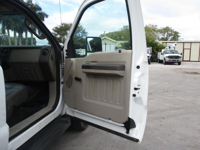 A white truck is parked in a parking lot with its doors open