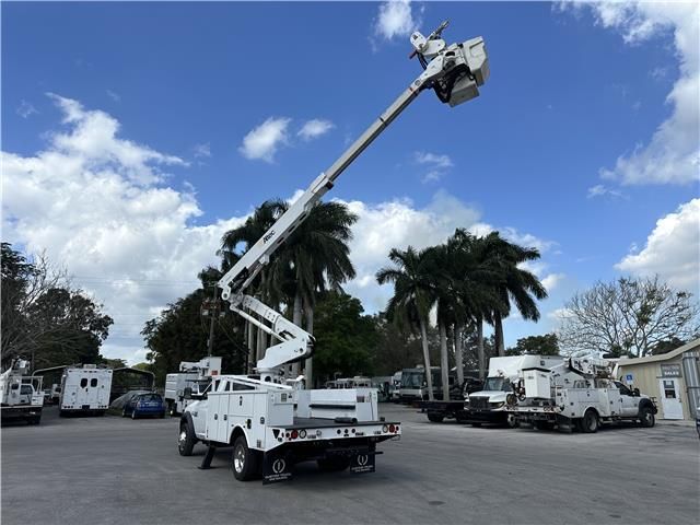 A white truck with a crane on the back is parked in a parking lot