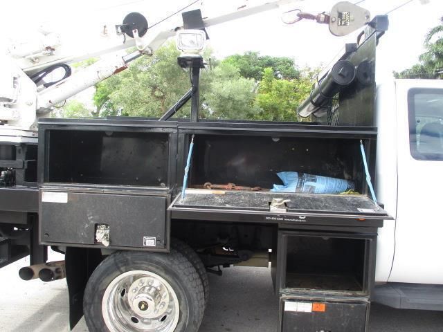 A white truck with a crane on the back is parked in a parking lot.