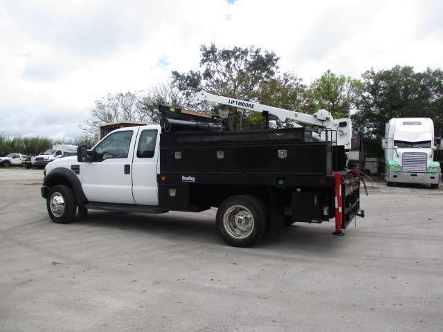 A white truck with a crane on the back is parked in a parking lot.