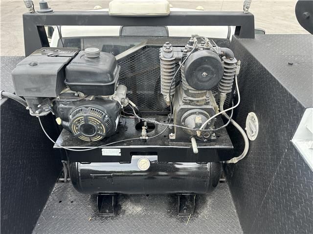 An air compressor is sitting inside of a truck bed