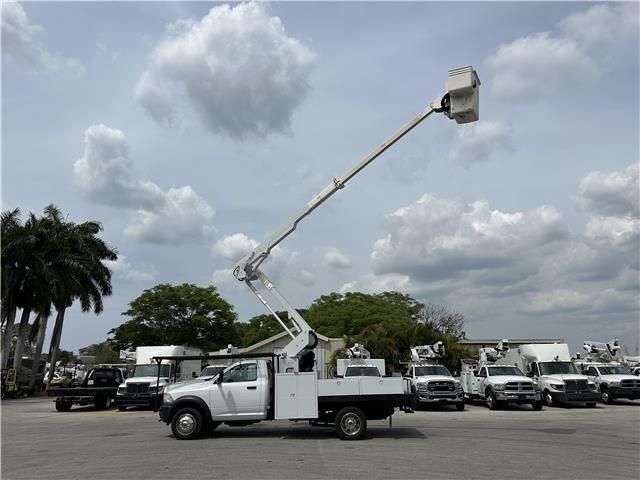 A white truck with a bucket on the back is parked in a parking lot.