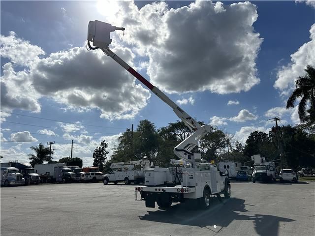 A white truck with a crane on the back is parked in a parking lot
