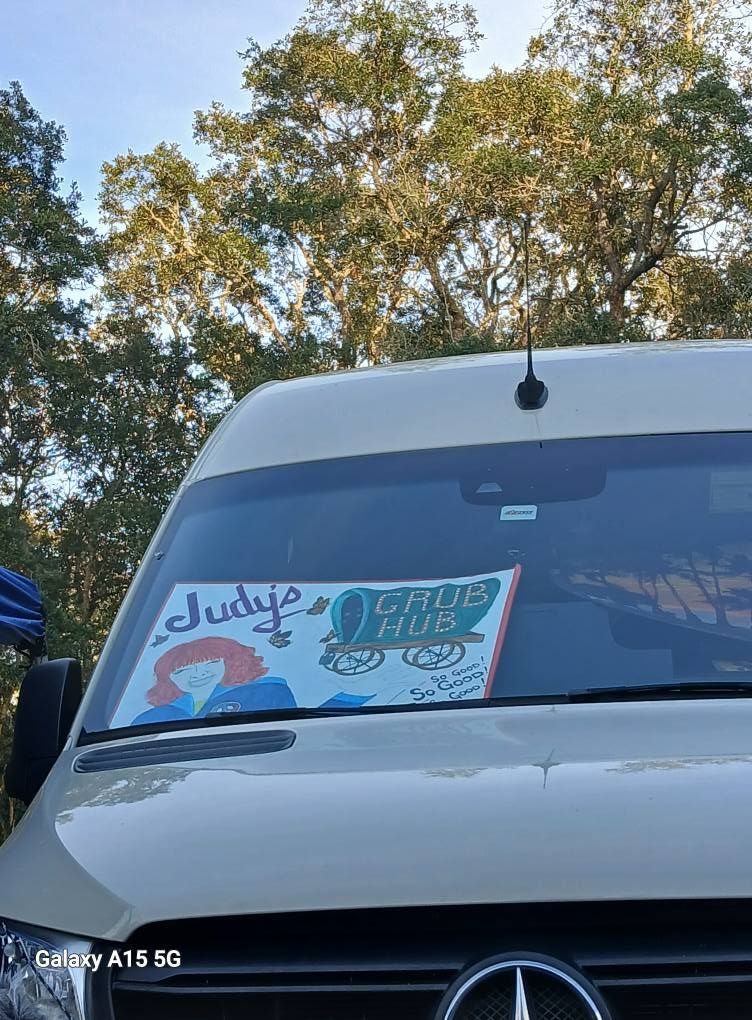 A white van with a sign on the windshield that says grub hub.