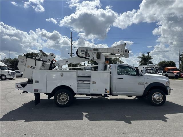 A white utility truck with a crane on the back is parked in a parking lot.