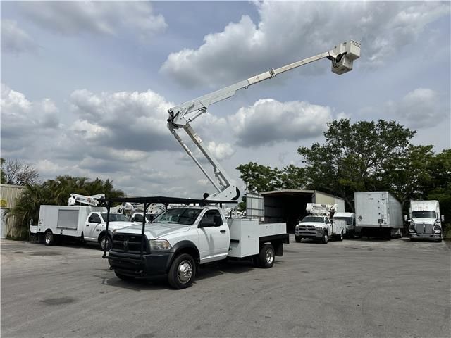 A white truck with a crane on the back is parked in a parking lot.
