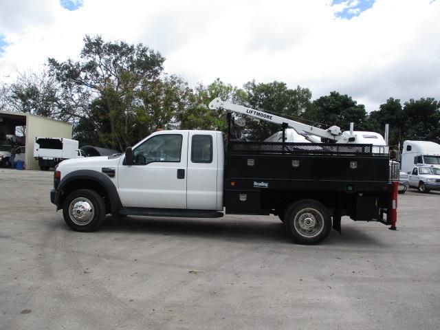 A white truck with a black bed is parked in a parking lot