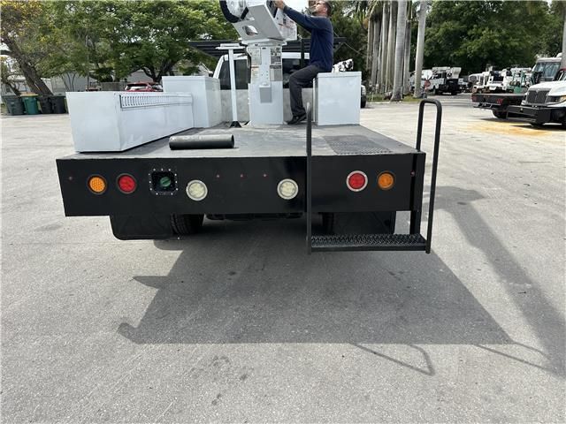 A man is sitting on the back of a truck in a parking lot.