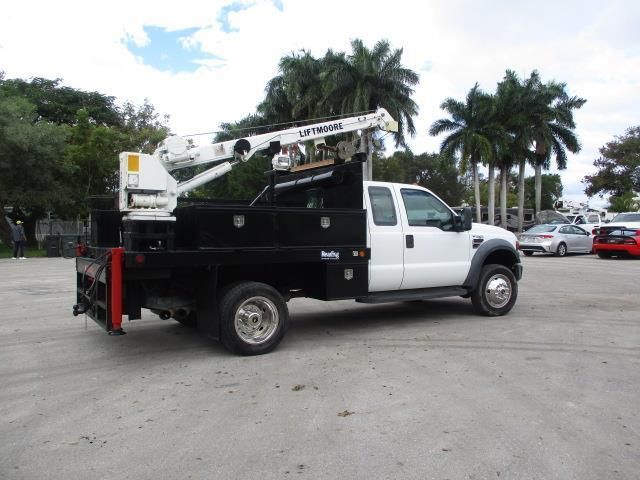 A white truck with a crane on the back is parked in a parking lot.
