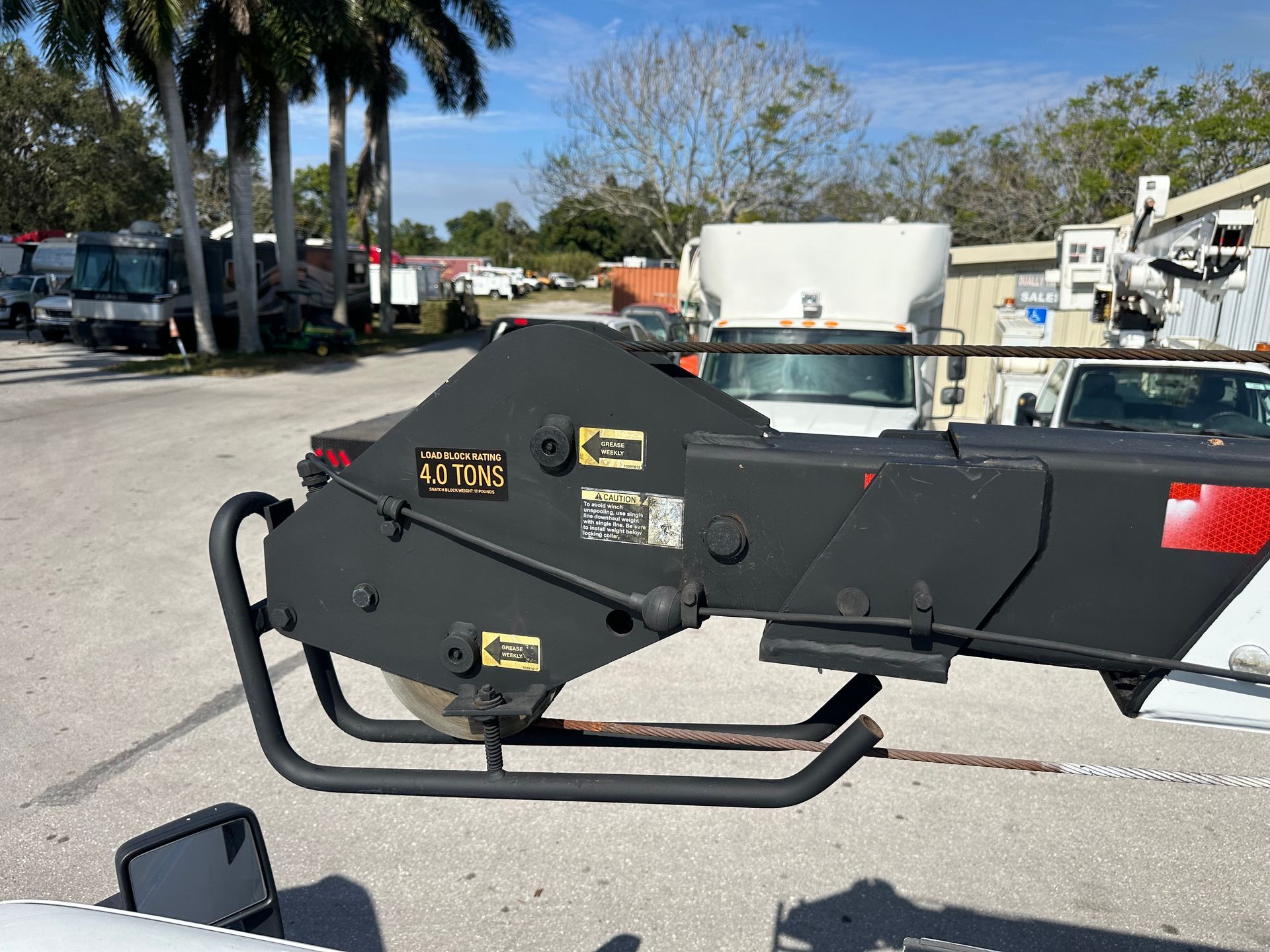 A tow truck with a crane attached to it is parked in a parking lot.