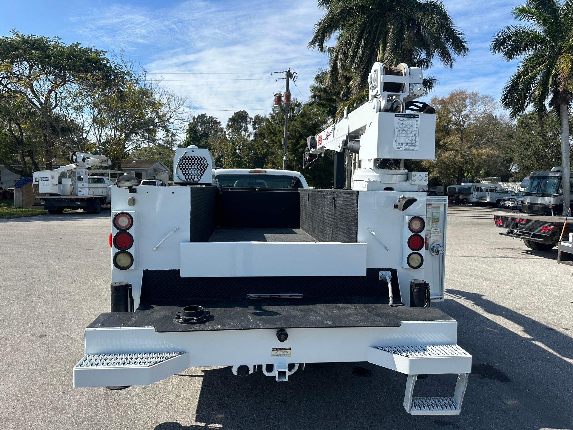 A white utility truck is parked in a parking lot
