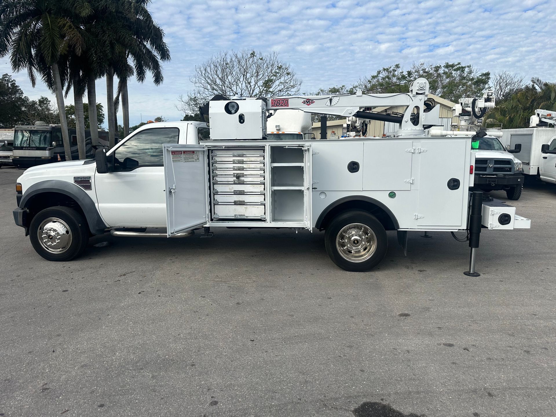 A white utility truck is parked in a parking lot.