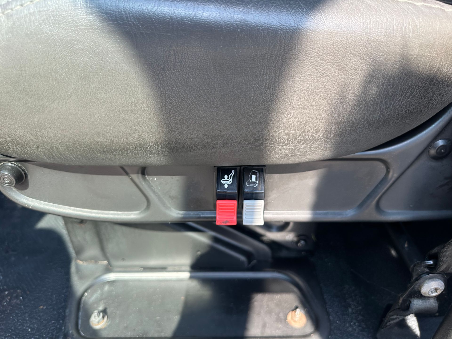A close up of a car seat with a red button on it.