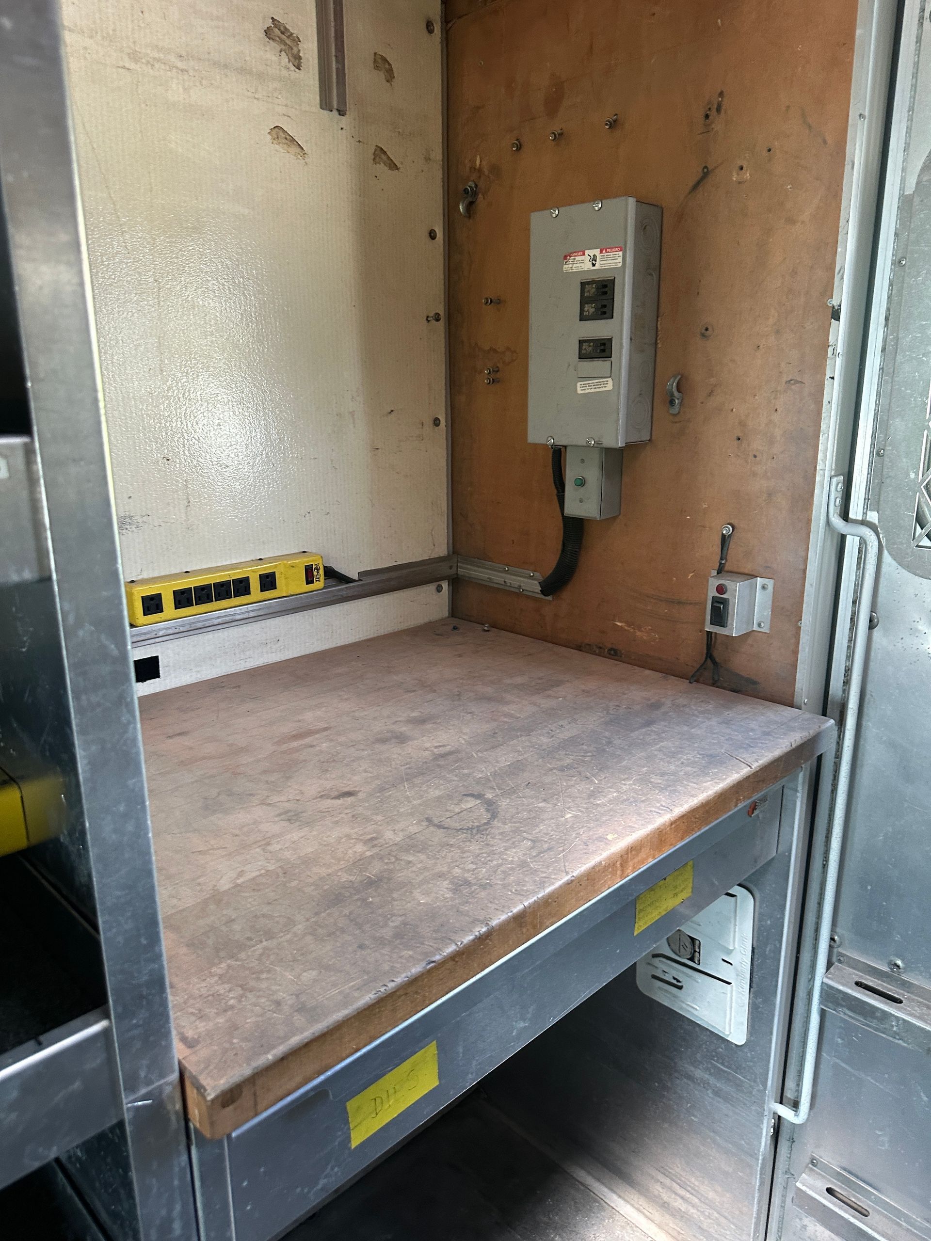 A wooden table with a switch on the wall next to it.