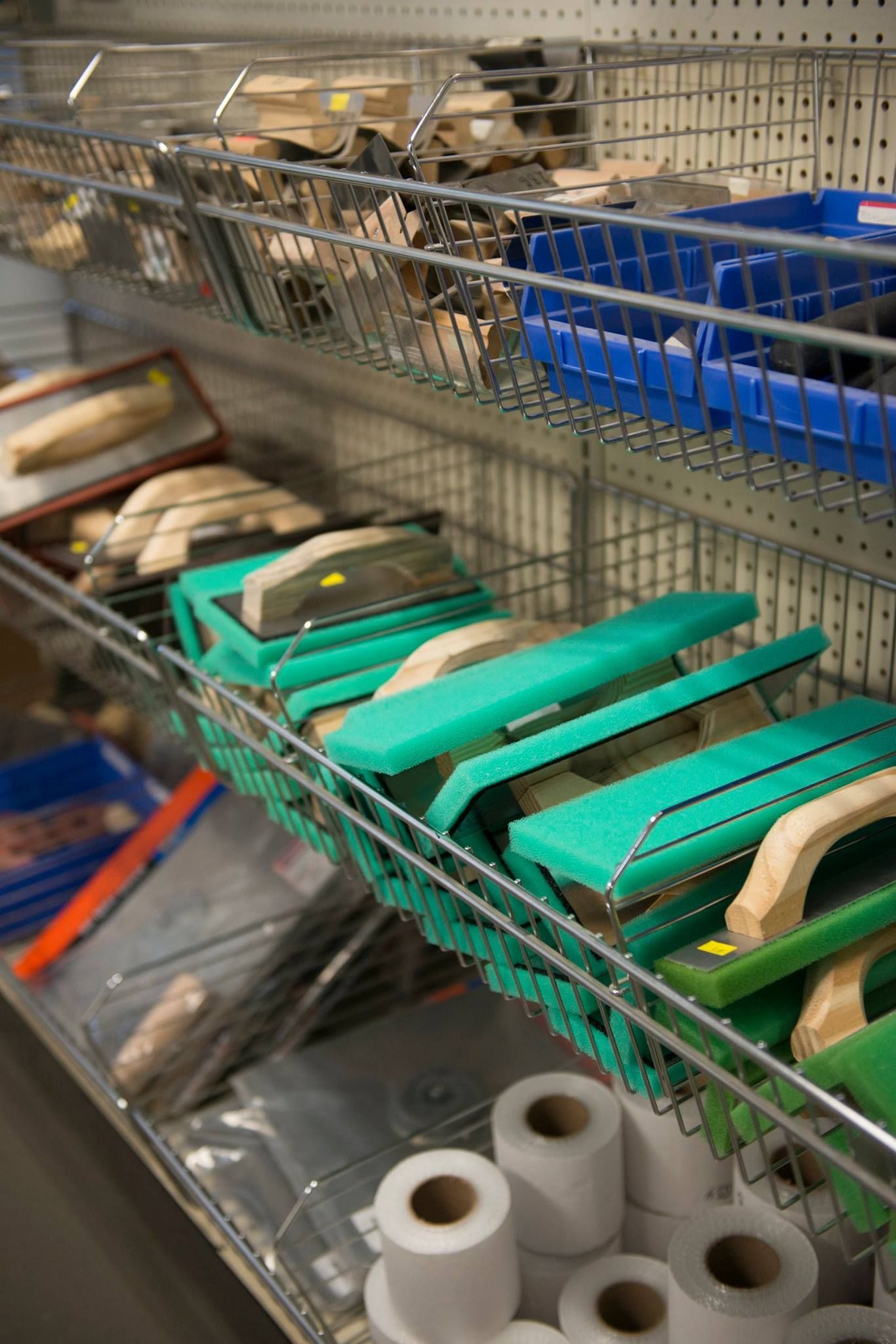 A shelf filled with a variety of tools and rolls of toilet paper.