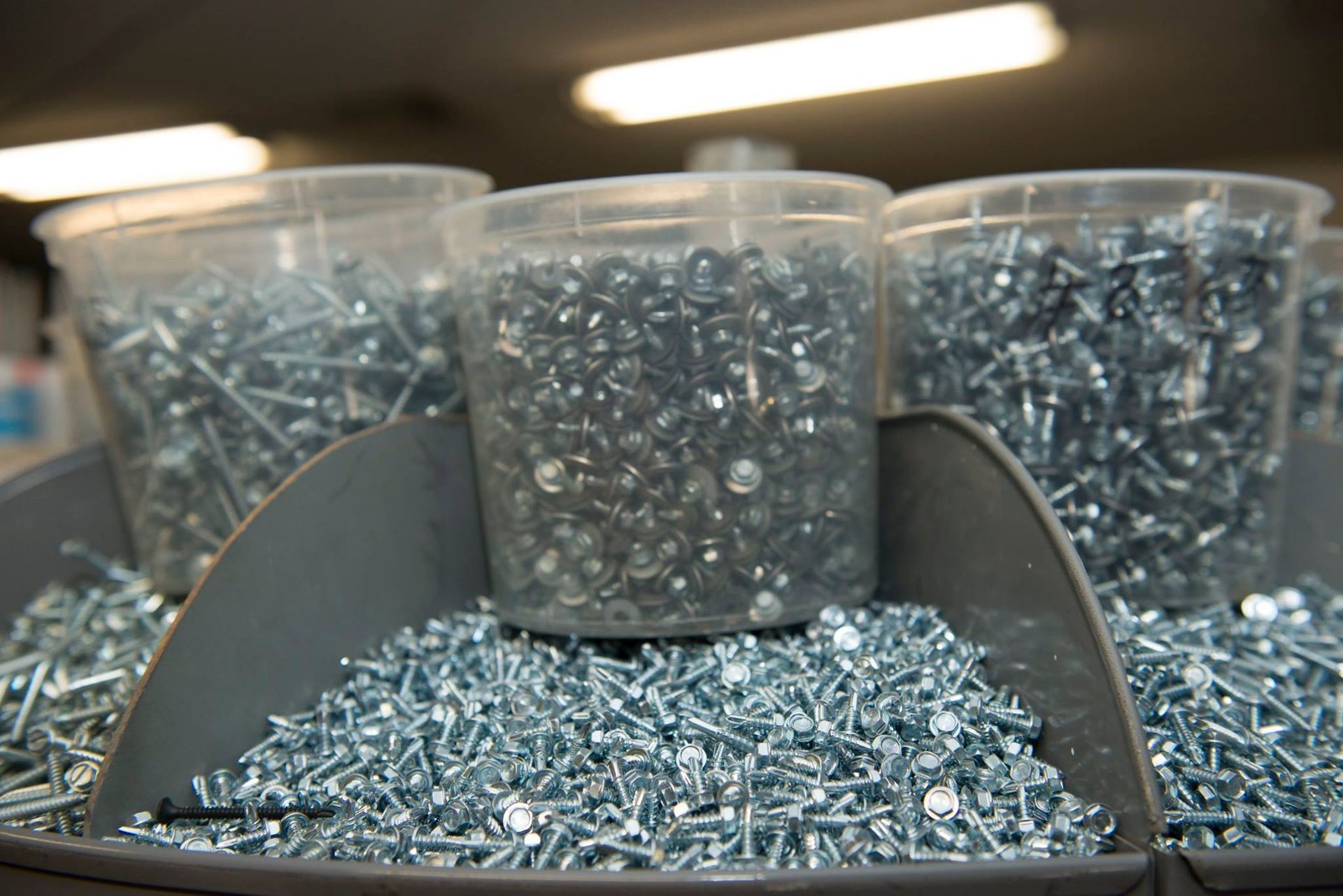 A pile of nuts and bolts in plastic cups on a tray