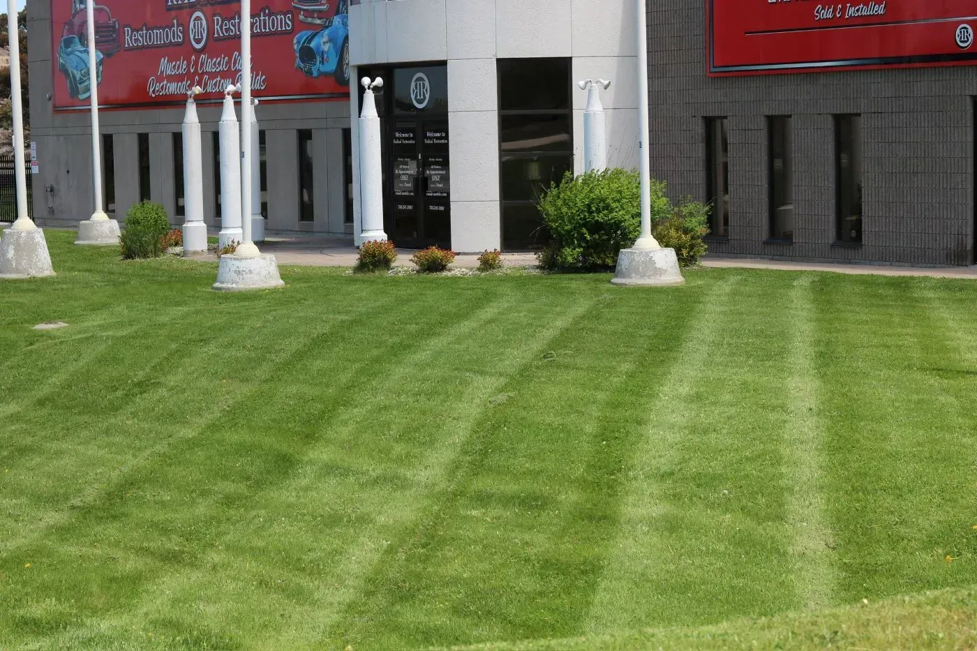 Green lawn in front of a building with alternating rows of mowed grass.