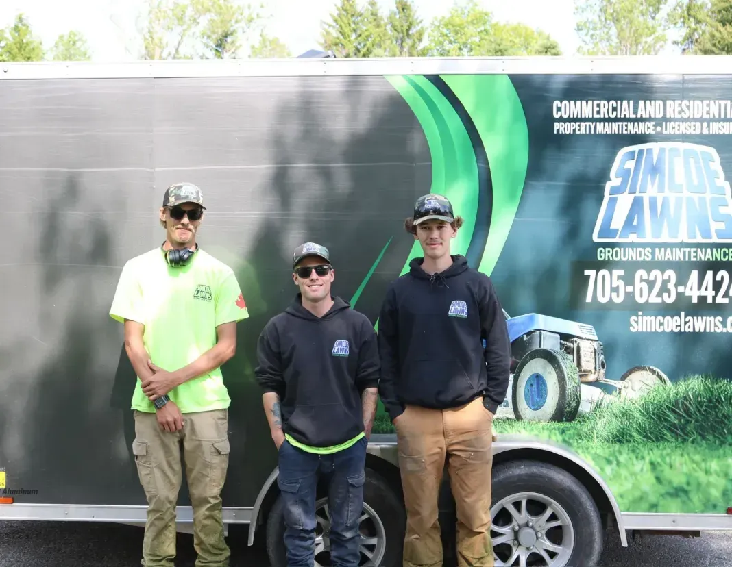 Three men stand in front of a trailer with 