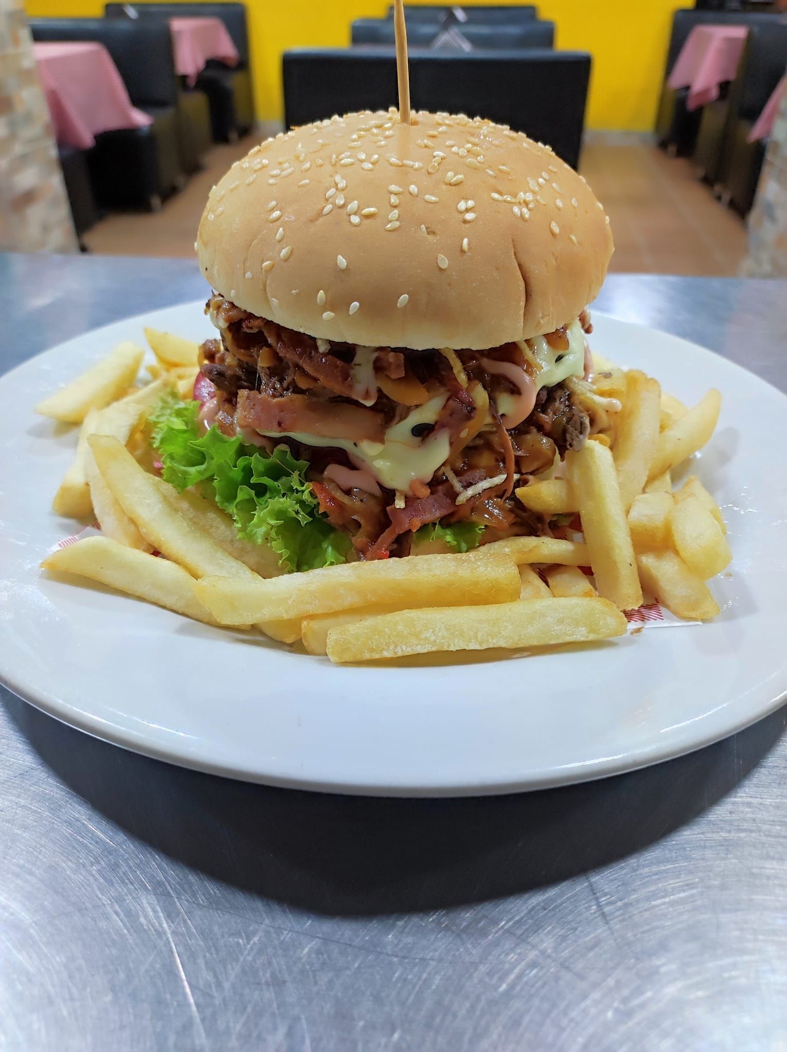 Hamburguesa con patatas fritas en un plato; entorno de restaurante.