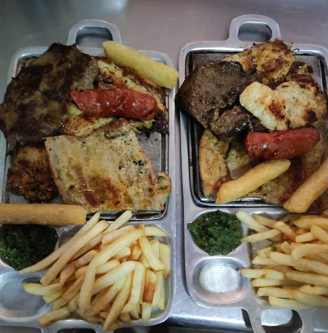 Un hombre con uniforme azul repara un aire acondicionado montado en una pared blanca. Usa un destornillador.