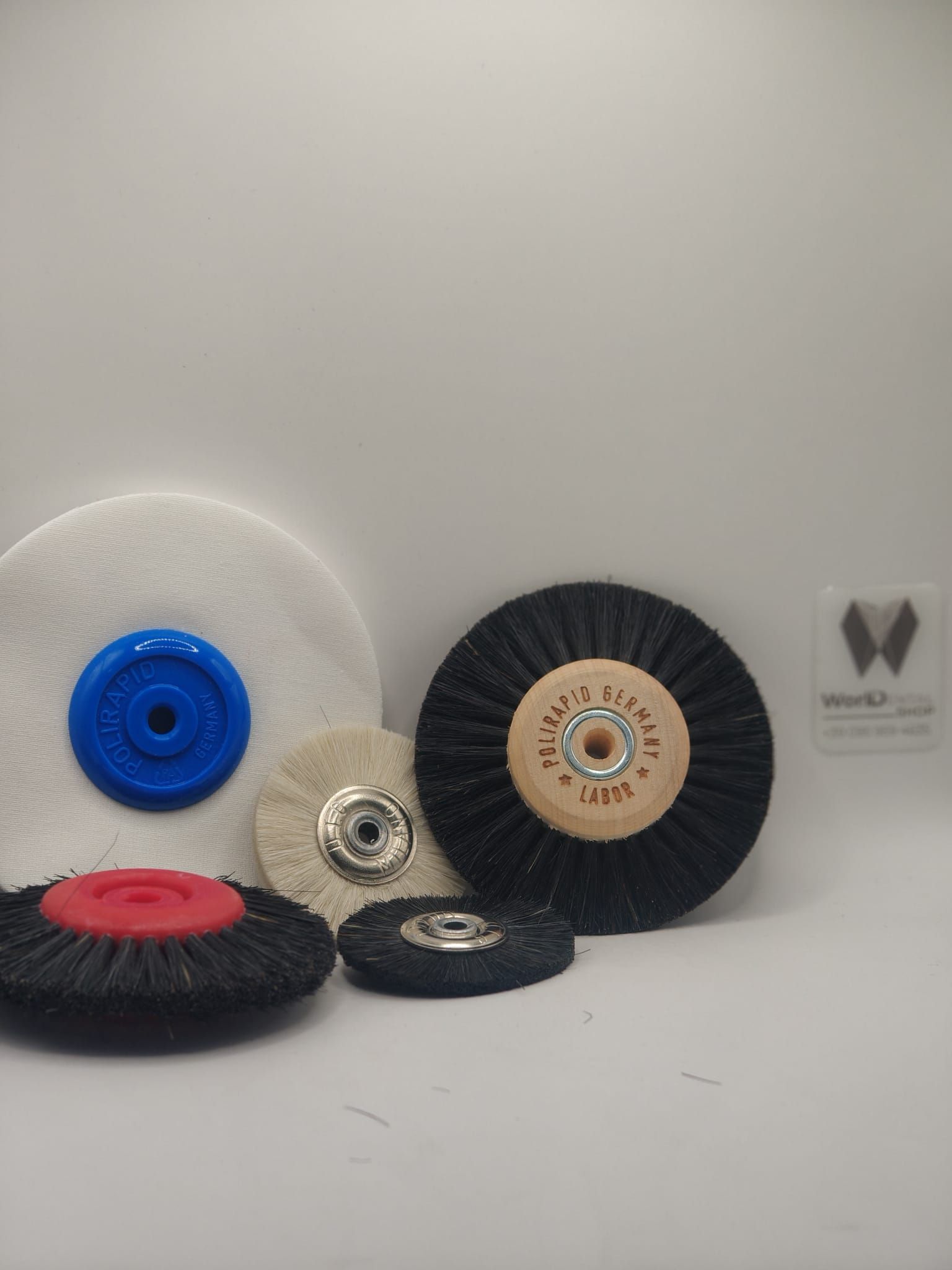 Una selezione di cinque dischi abrasivi e lucidanti circolari di varie dimensioni, colori e texture su sfondo bianco.