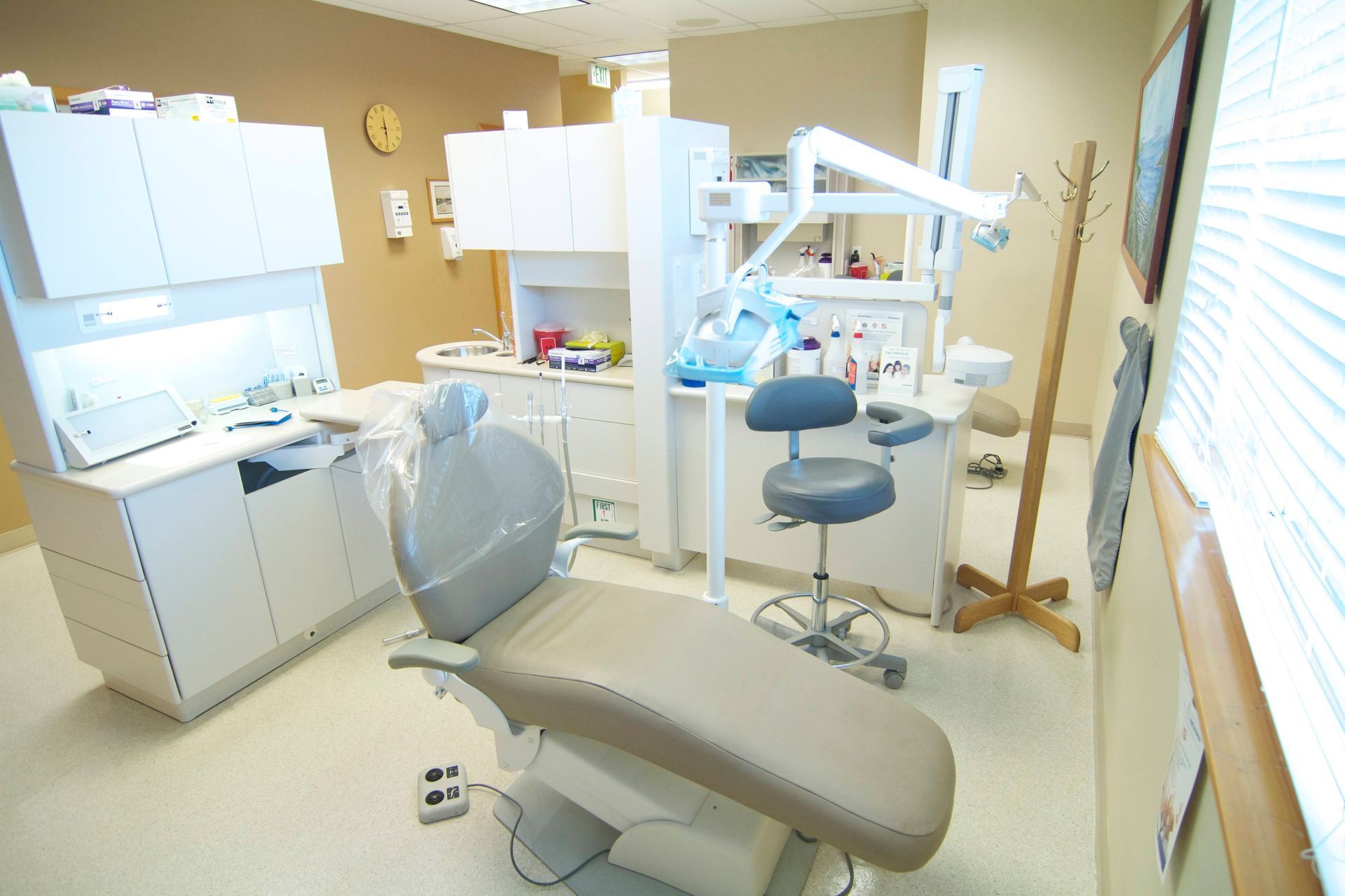 Dental examination room, equipped with chair, cabinets, and overhead light.