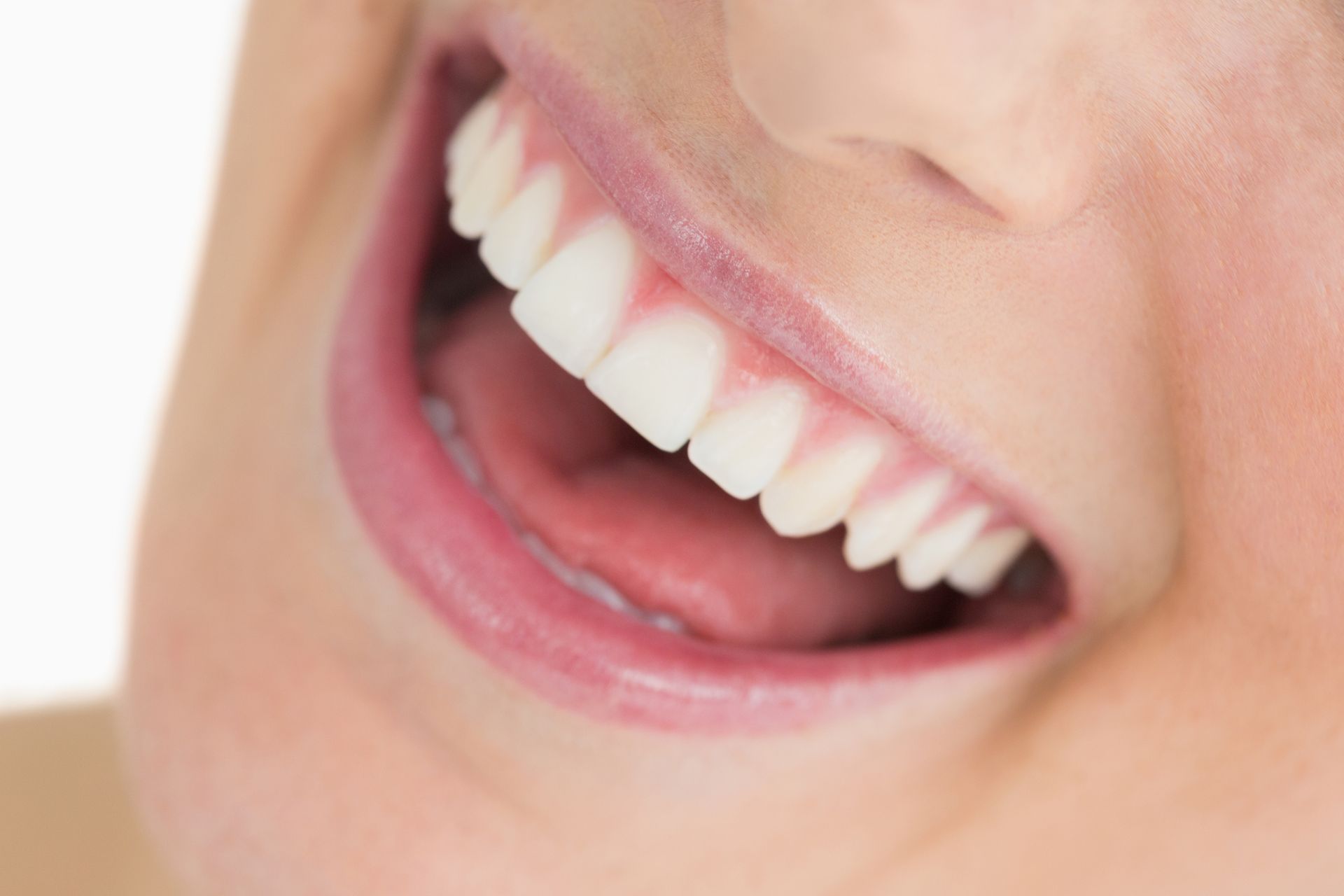 Close-up of a person's smiling mouth, showing bright white teeth, pink gums, and a slightly open mouth.